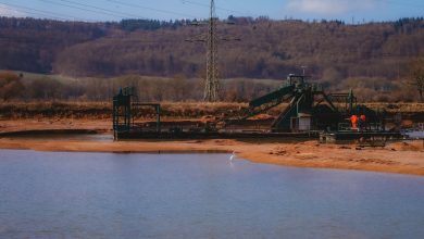 Operação de mineração a céu aberto próxima a um corpo d’água durante o dia