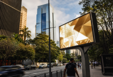 Painel digital de mídia exterior em avenida urbana com circulação de pessoas e veículos