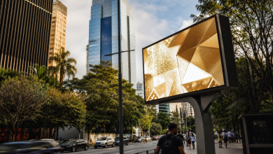 Painel digital de mídia exterior em avenida urbana com circulação de pessoas e veículos