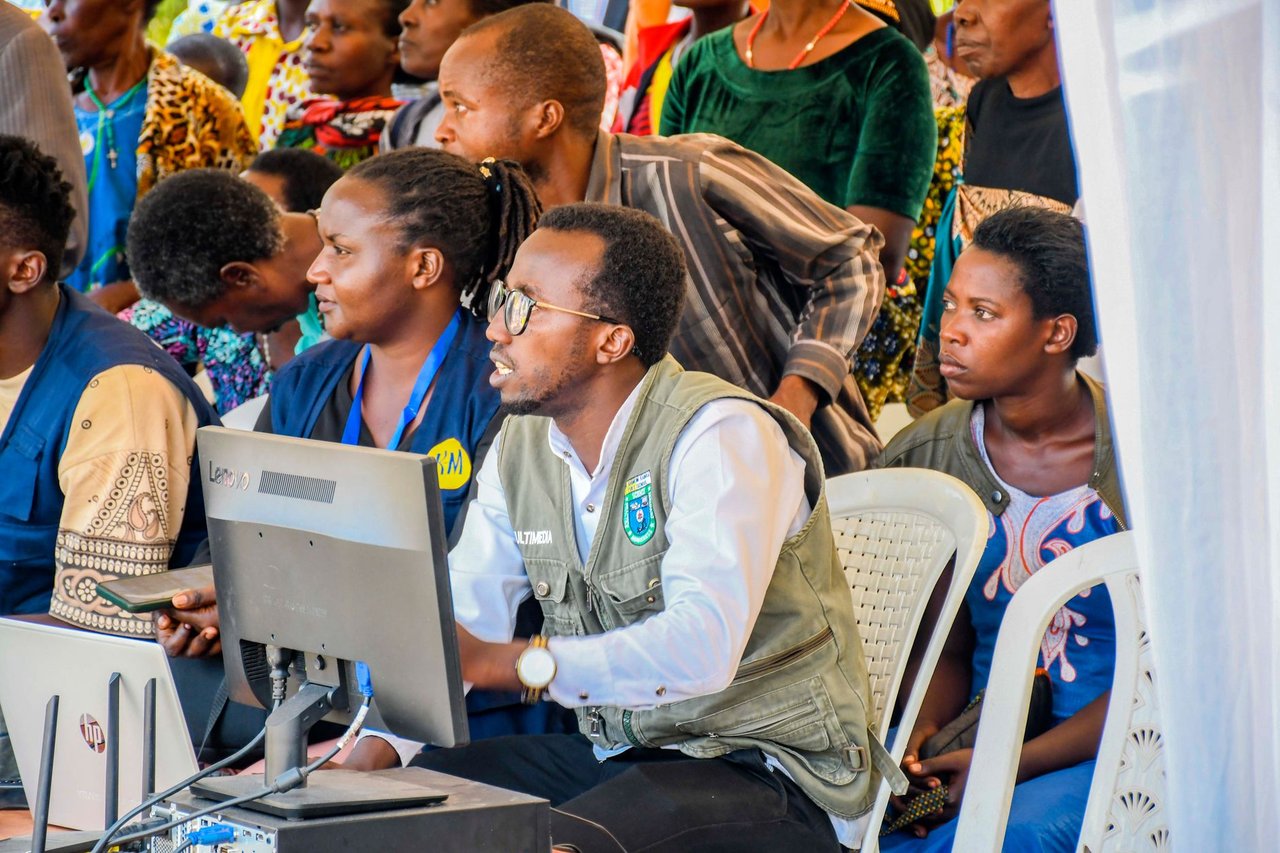 Grupo diverso de adultos participa de uma atividade comunitária envolvendo tecnologia.