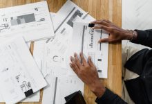Profissional analisa documentos financeiros sobre uma mesa de trabalho.